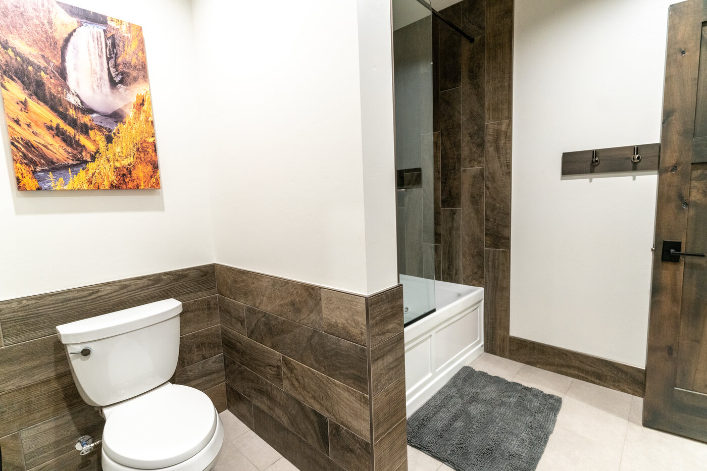 Beautiful Views — bathroom with deep tub, wood-look tile, and framed Yellowstone canyon print