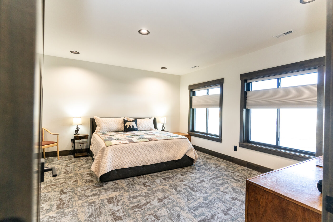 Beautiful Views — king bedroom with quilted bedding and abundant windows facing the lake