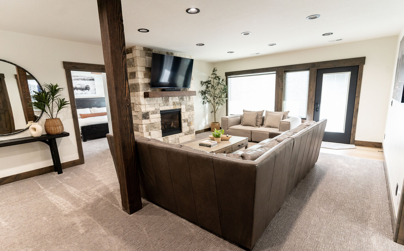 Lodge at Cutthroat Landing — lower rec room with brown sectional facing stacked-stone fireplace and TV