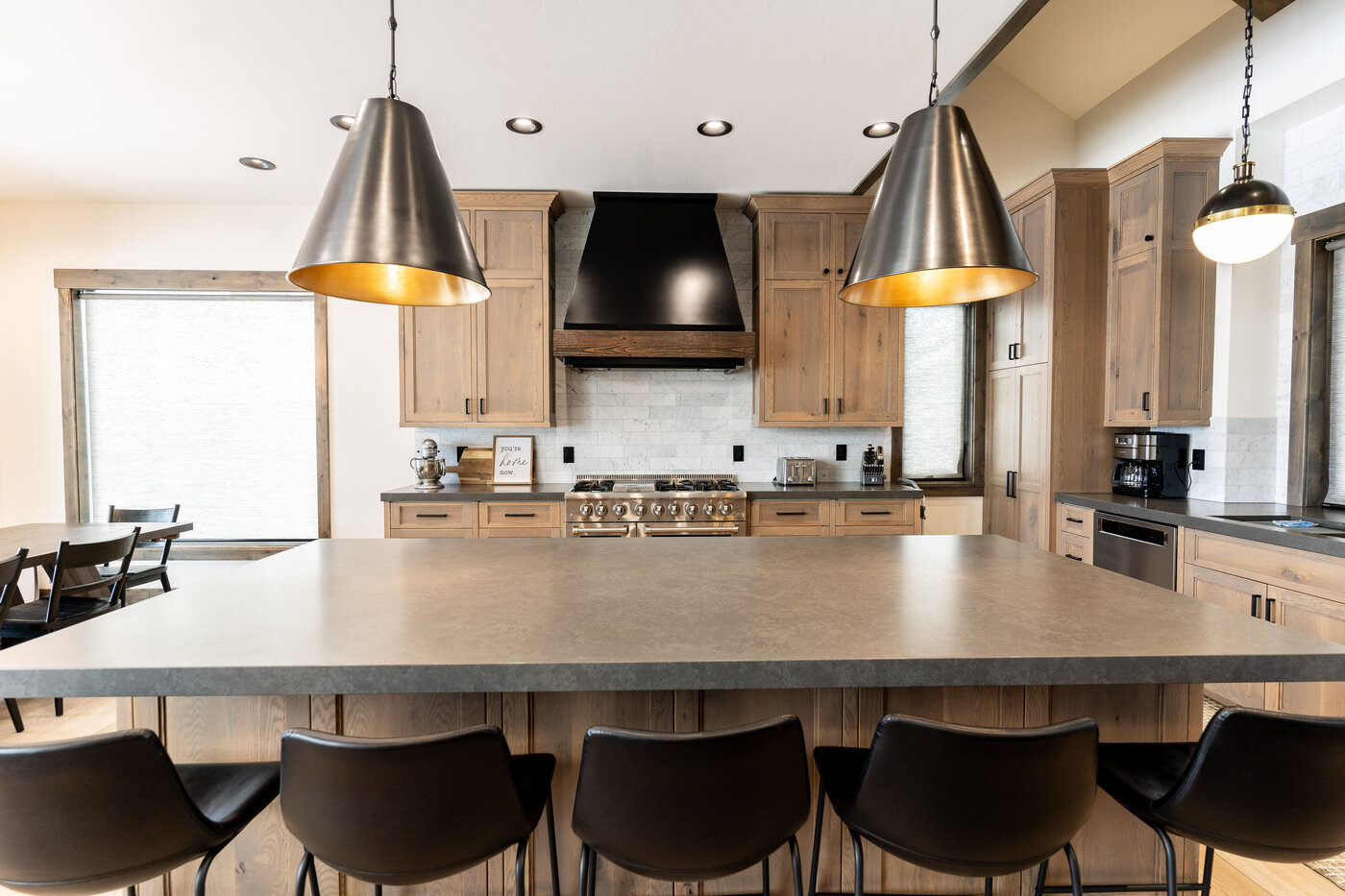 Lodge at Cutthroat Landing — kitchen wide with concrete-top island, brass pendants, and black hood