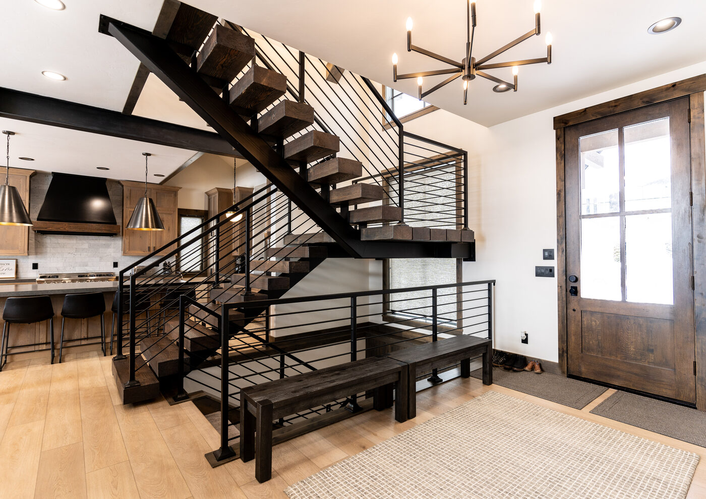 Lodge at Cutthroat Landing — entry foyer with floating staircase, knotty-pine door, and starburst chandelier