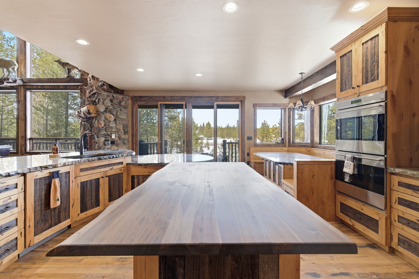 Riverfront Wildlife Lodge — long live-edge walnut dining table with deck doors and forest view