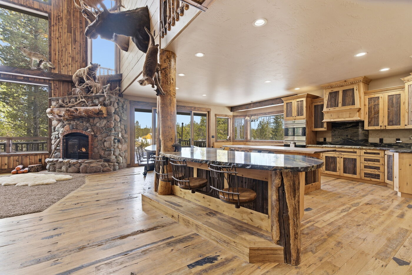 Riverfront Wildlife Lodge — great room stone fireplace with log columns opening to the kitchen