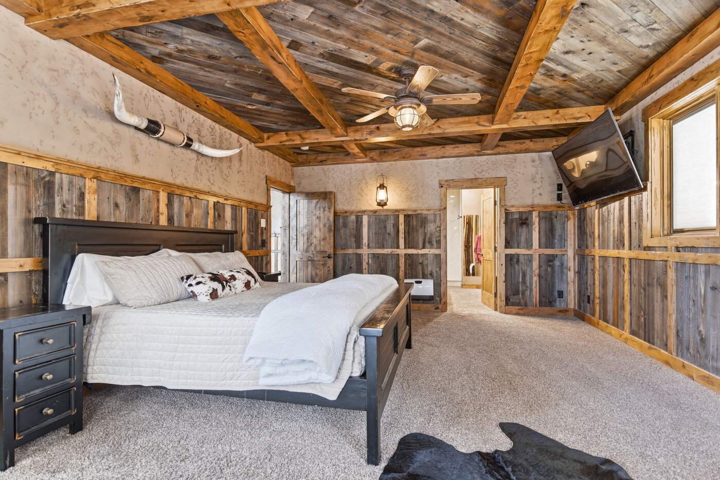 Riverfront Wildlife Lodge — king bedroom with reclaimed-board wainscoting and skull mount