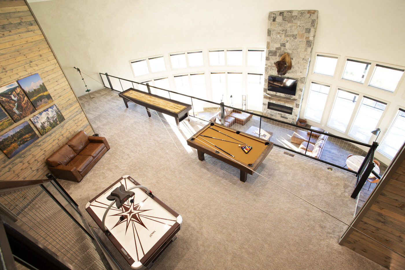 Teton View Retreat — West Cabin — game room looking down from the upper floor showing pool table and stone fireplace
