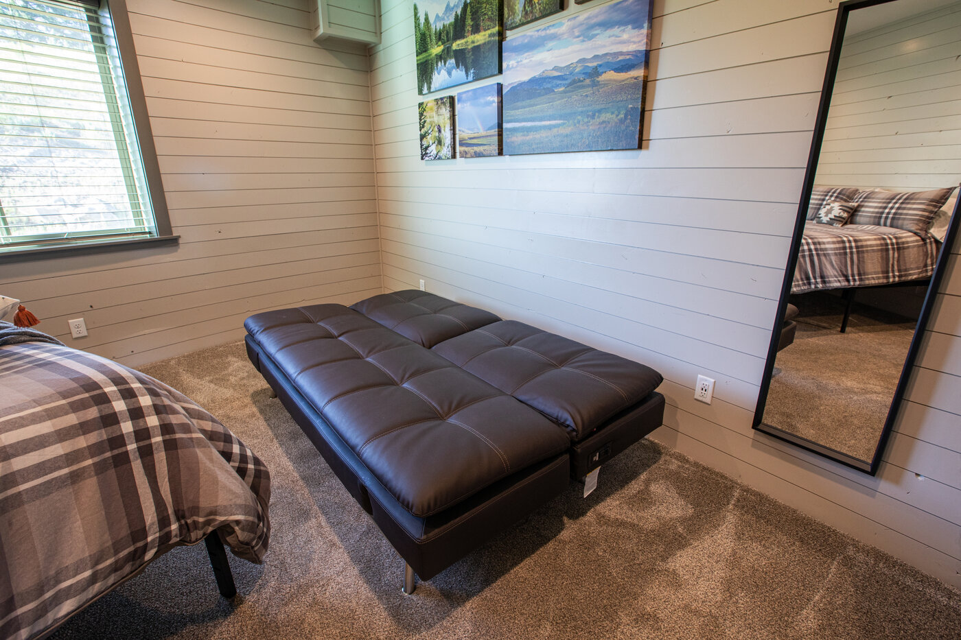 Teton View Retreat — West Cabin — bedroom with chocolate futon, plaid bedding, and framed nature photography