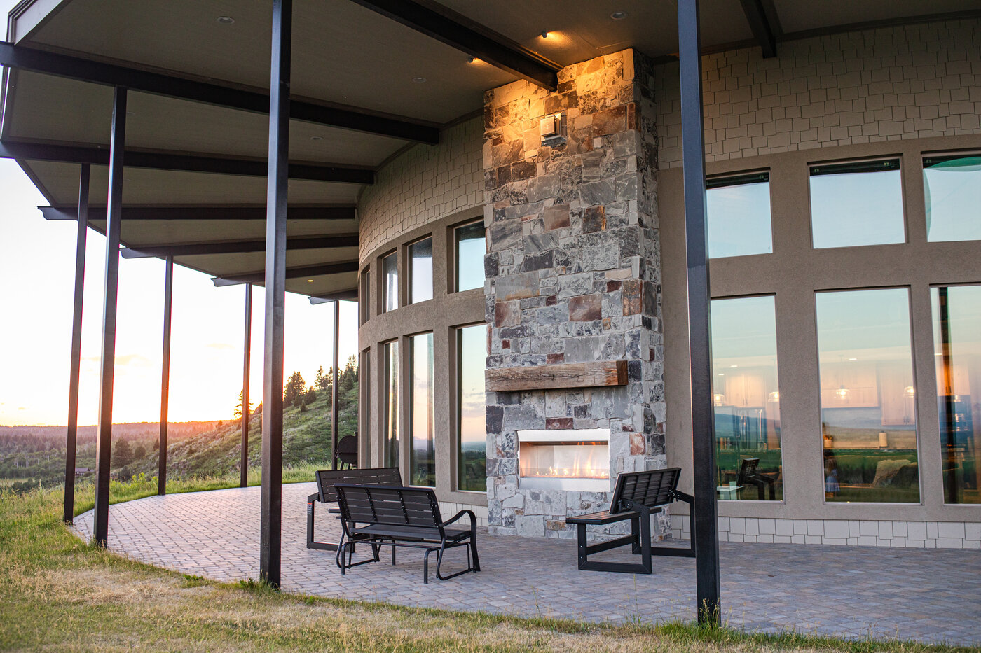 Teton View Retreat — West Cabin — stone fireplace on the covered porch with sunset on the horizon