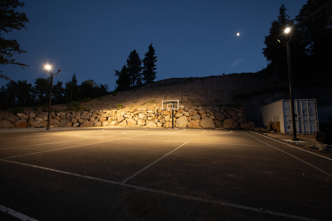 Teton View Retreat — West Cabin — lit basketball court at night with the moon overhead