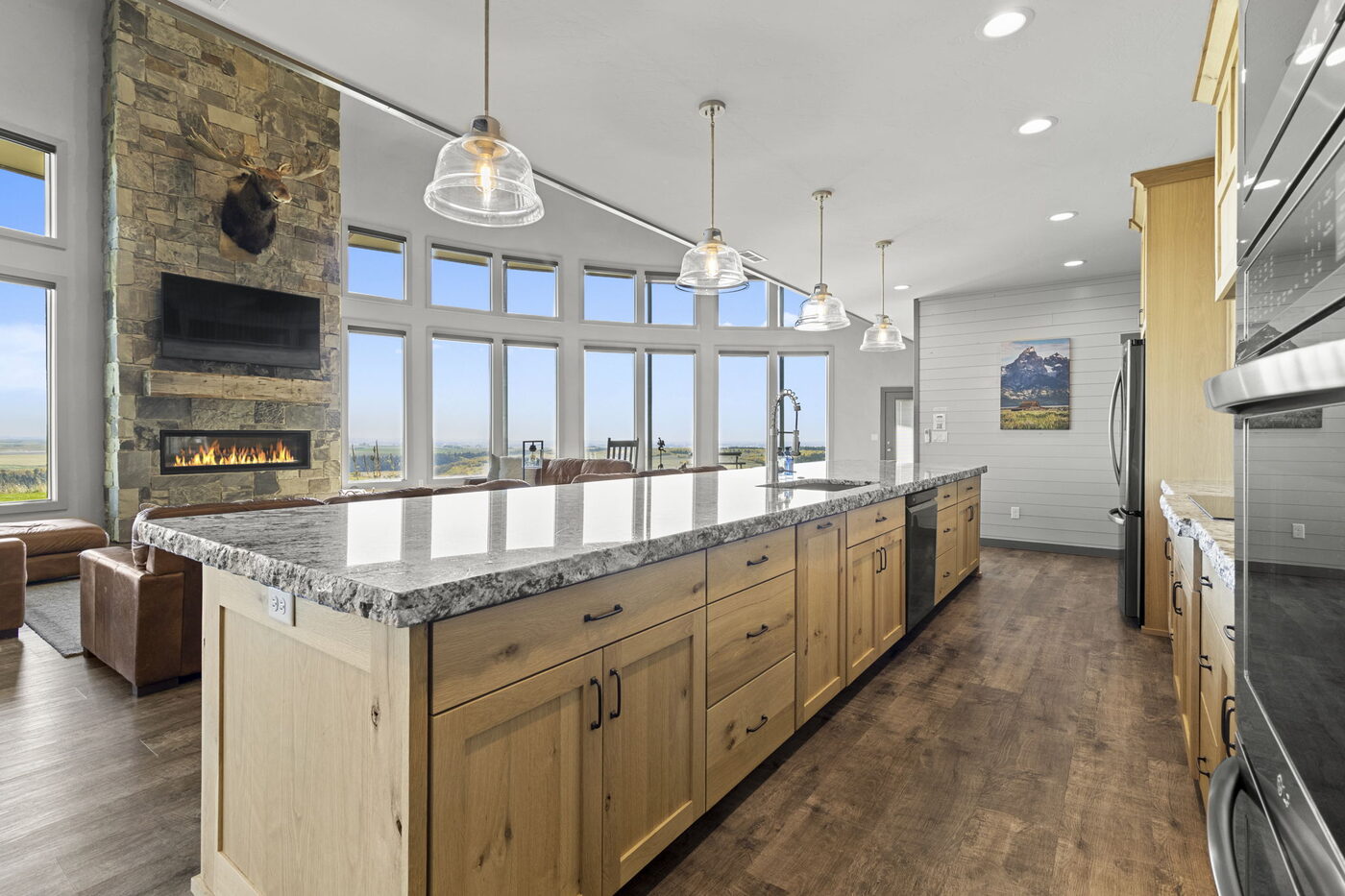 Teton View Retreat — West Cabin — kitchen with long granite island, pendant lights, and Tetons through the windows