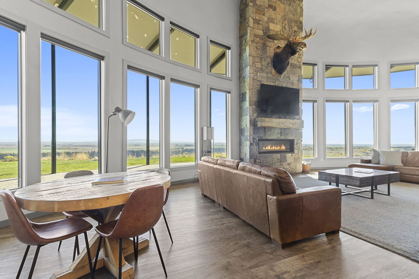 Teton View Retreat — West Cabin — great room with leather sofas, mounted moose, and panoramic windows