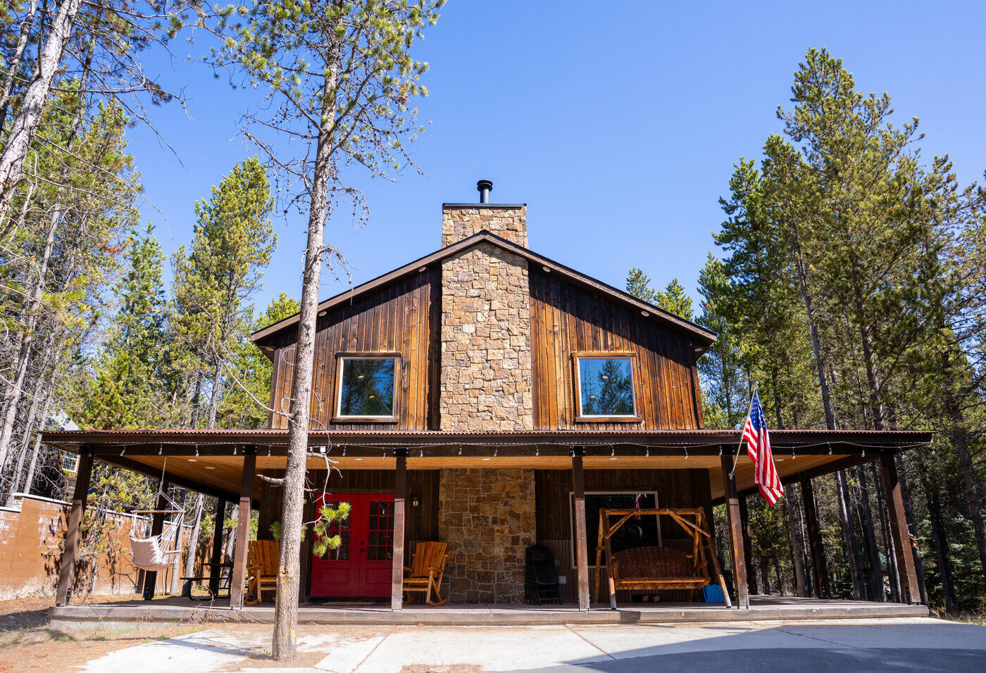 Trails End Lodge — front exterior with stone facade, red doors, and wraparound porch