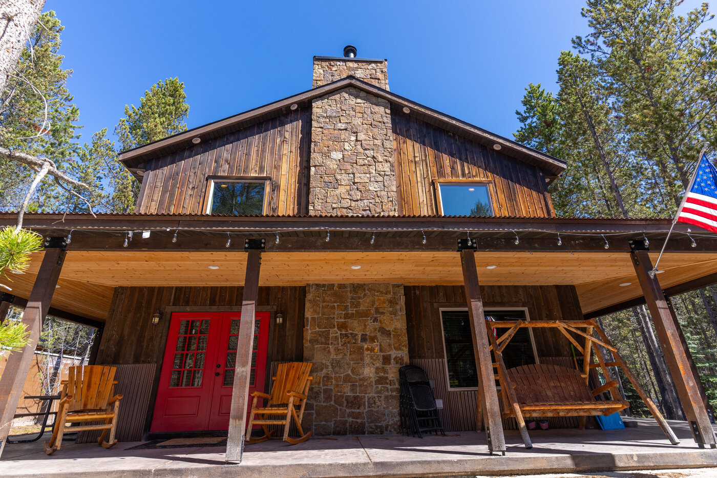Trails End Lodge — cabin front detail with the red double doors, rocking chairs, porch swing
