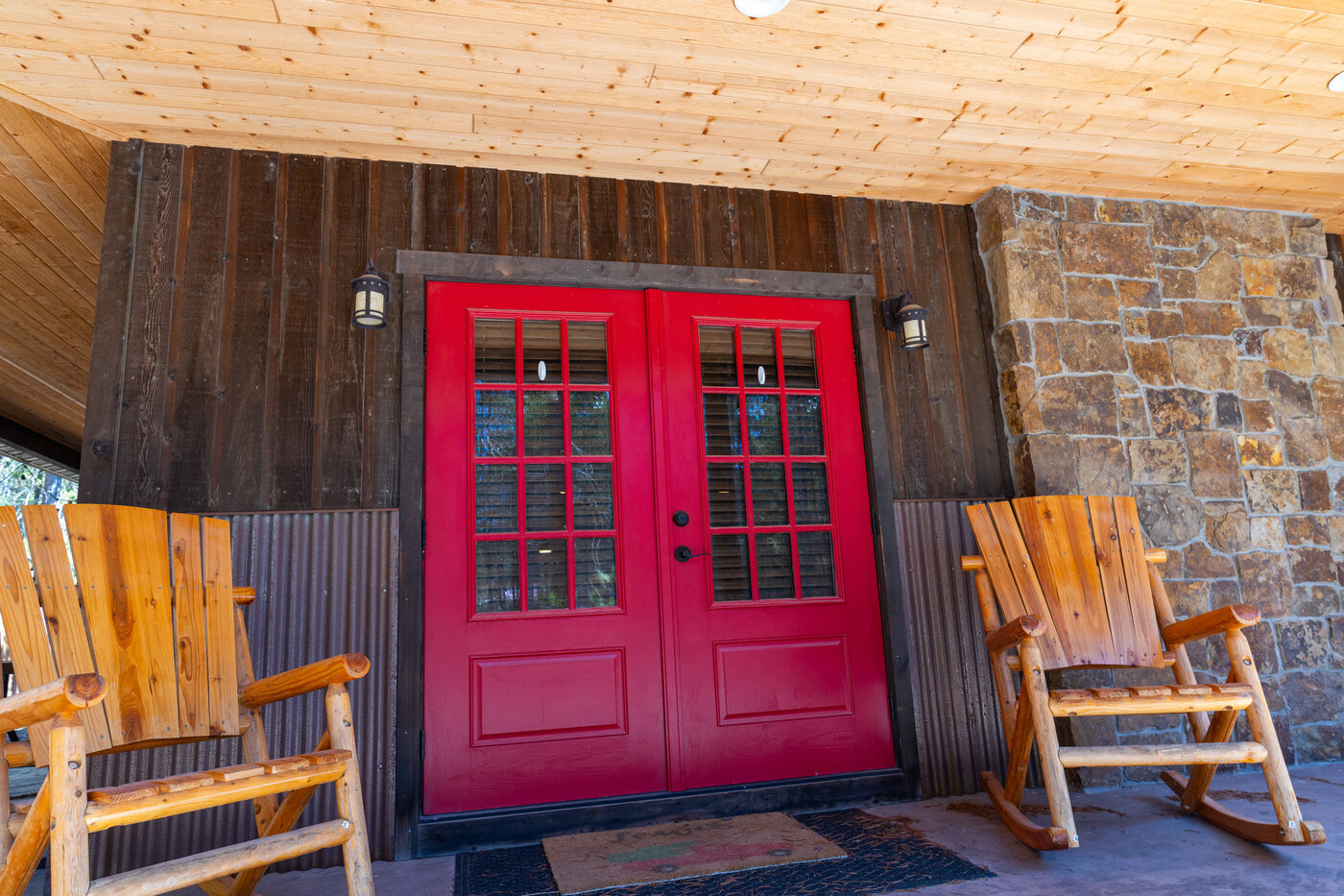 Trails End Lodge — red double doors with hand-built log rocking chairs flanking the entry