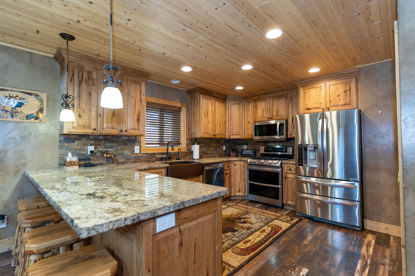 Trails End Lodge — kitchen with hickory cabinets, stacked-stone backsplash, and granite peninsula