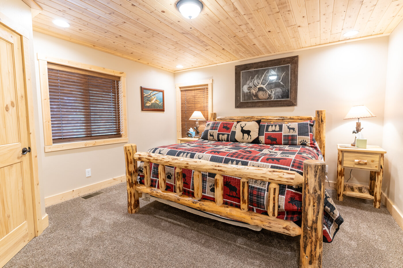Trails End Lodge — log queen bedroom with plaid bedding and elk artwork