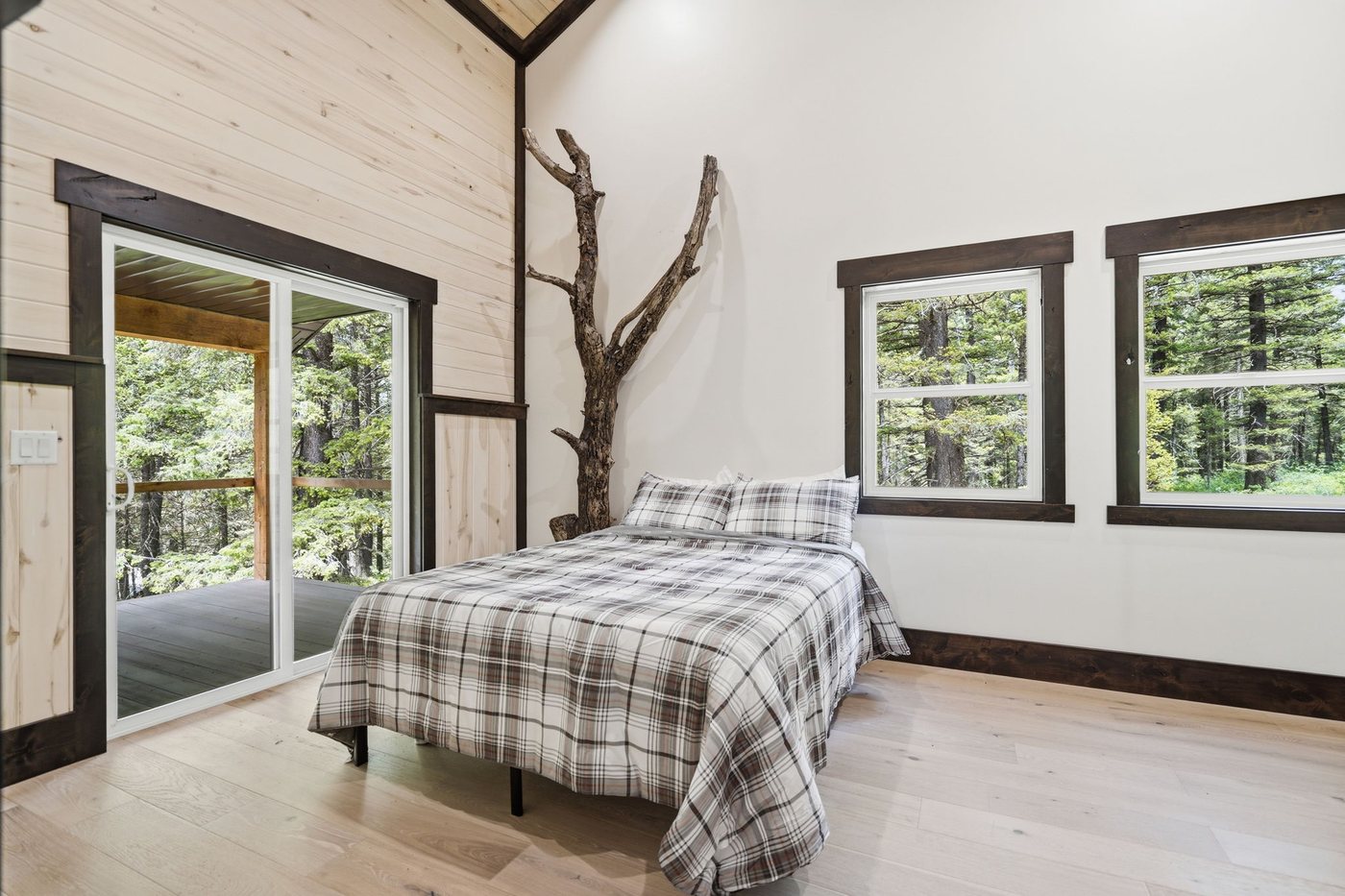 The Treehouse — bedroom with plaid bedding and forest windows