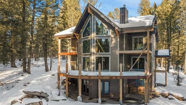 The Treehouse exterior in winter — two-story glass front under the pines